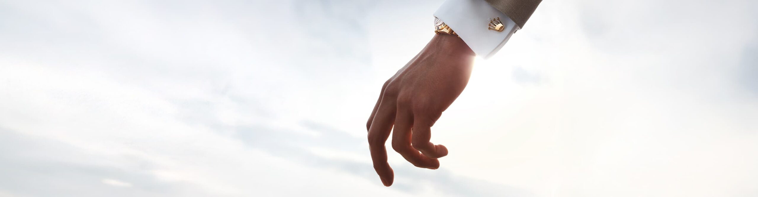 A model wearing Rolex 'Crown' cufflinks in 18ct yellow gold with a matching gold Rolex Watch. Rolex Accessories - Chang Ein Hong