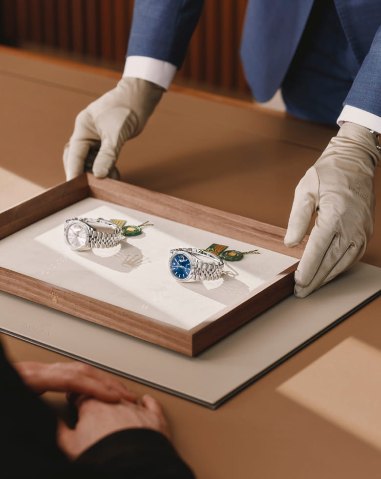 Rolex specialist presenting two watches to a client on a wooden tray - Chang Ein Hong