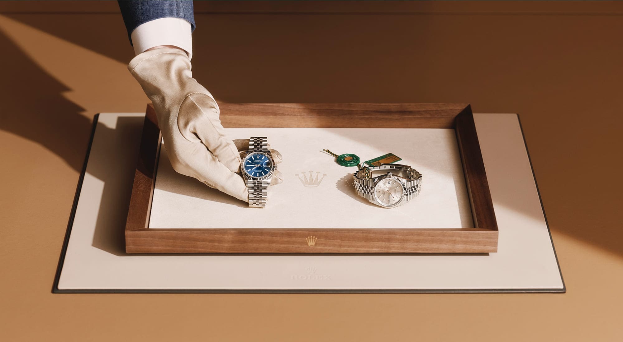 Gloved hand presenting two Rolex watches on a wooden tray - Chang Ein Hong